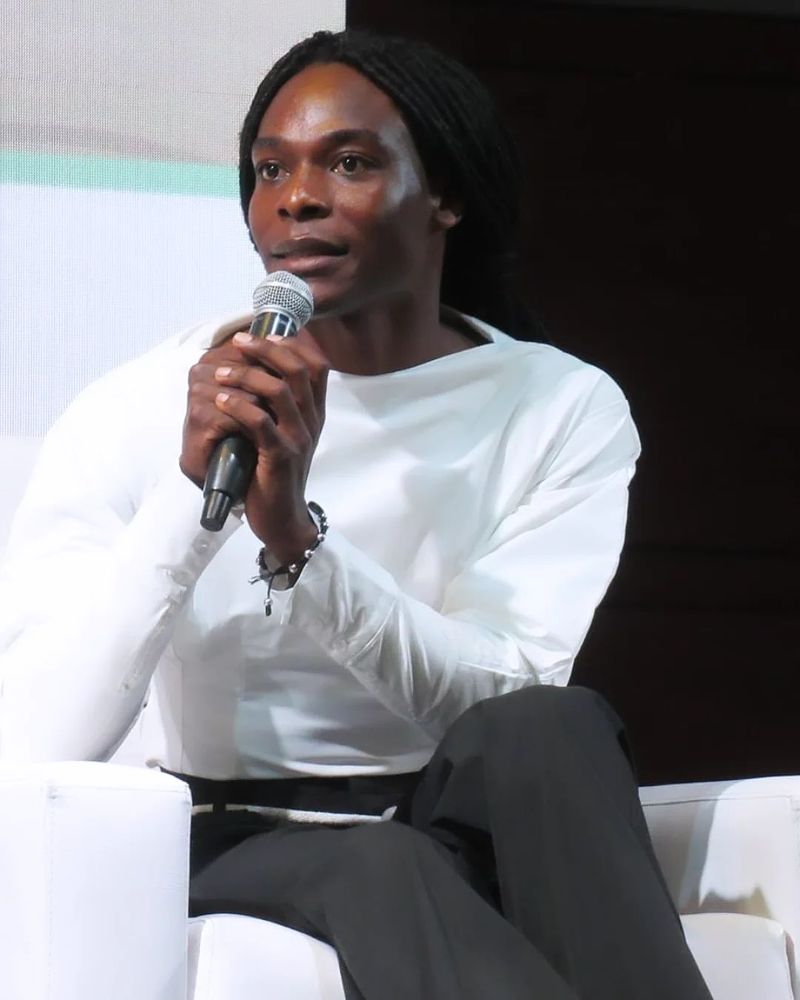 Deyner Caicedo Camacho speaking into a microphone, seated on stage during a panel